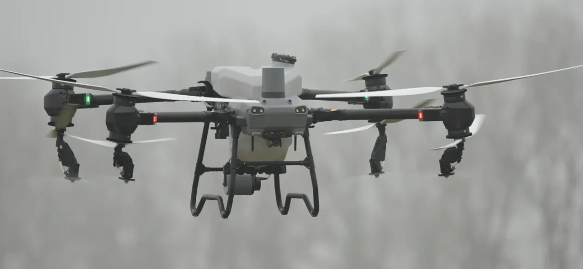 Eine DJI Agras T50 Landwirtschaftsdrohne befindet sich im Flug und sprüht Pflanzenschutzmittel auf ein Feld.
